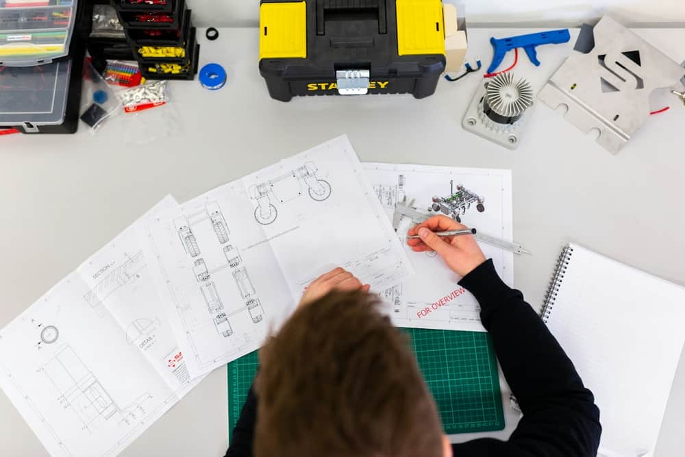 Technician planning a job at a workbench with tools and drawings